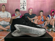 Side view of a black Adidas basketball sneaker with a silver textured panel and black high-top upper.