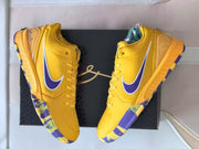 Pair of yellow sneakers viewed from above with purple side detailing and contrasting outsole sections.