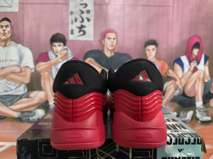 Rear view of red and black Adidas basketball sneakers displayed on a box, with Adidas logos on the heels.