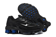 Pair of black Nike Shox R4 sneakers showing the side profile and outsole with blue accents.