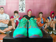 Front view of green basketball shoes with patterned laces and blue-orange accents.