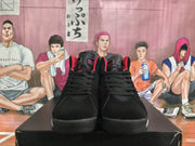 Front view of the paired black high-top sneakers with black laces, padded tongues, and red and purple details.