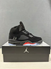 Side profile of the black and red Jordan Air Jordan 5 sneaker on a black shoebox