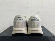 Rear view of gray and off-white New Balance U370 sneakers with navy heel branding.