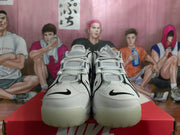 Front view of white Nike sneakers with black Swoosh accents and perforated panels.