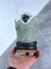 Rear view showing the embroidered Jordan logo, green upper, black heel section, and gum-colored outsole.