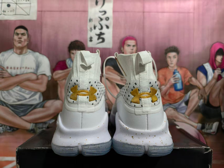 Rear view of white high-top basketball shoes with gold Under Armour heel logos and speckled midsoles