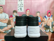 Rear view of black and white high-top basketball sneakers showing the padded black collars, white heel sections, and textured outsoles.