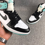 Close-up of the perforated white toe box, black overlays, black laces, and mint green tongue branding.
