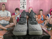 Front view of a pair of gray high-top basketball sneakers with black lace details and translucent outsoles.