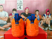 Rear view of orange Nike sneakers showing blue heel tabs and textured orange outsoles.