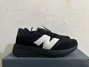 Side profile of a black New Balance U370 sneaker with a light-colored logo.
