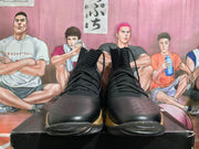 Front view of black lace-up high-top basketball shoes with gold-colored accents.