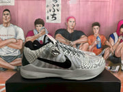 Side view of a Nike sneaker showing the black Swoosh, patterned upper, basketball-themed circular detail and light-coloured sole.
