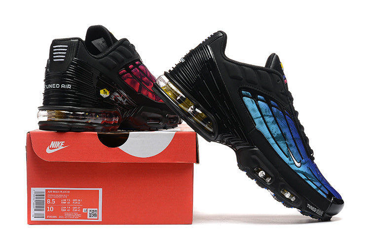 Black Nike Air Max Plus TN sneakers with blue and pink gradient panels displayed on a red shoe box.
