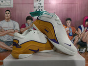 Angled view of the white and gold basketball sneakers with purple accents and visible Nike branding.