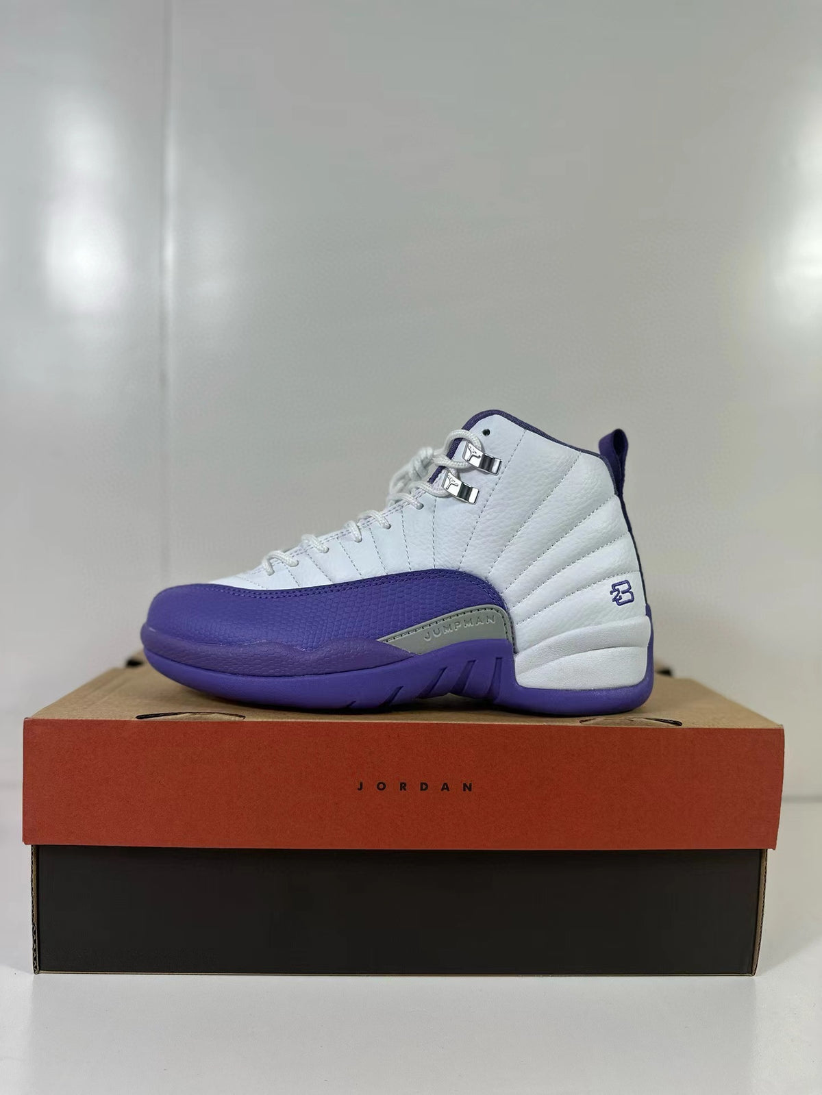 White and purple Air Jordan 12 Retro shown in profile on a shoebox