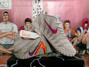 Pair of light pinkish-gray Nike Kyrie basketball shoes shown from the sides with multicolor graphics and textured soles