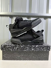 Pair of black low-top sneakers stacked on a patterned shoebox, showing the side panels, textured toe and heel accents, and pull tabs.
