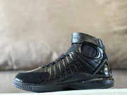 Side view showing the sculpted panels and oval ankle detail of the black high-top shoe.