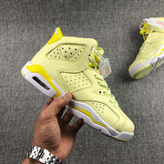 Handheld side profile showing the high-top shape, perforated upper, layered panels, white midsole, and yellow outsole accents.