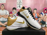 Pair of white Nike Kobe basketball shoes with gold accents and contrasting black and white laces