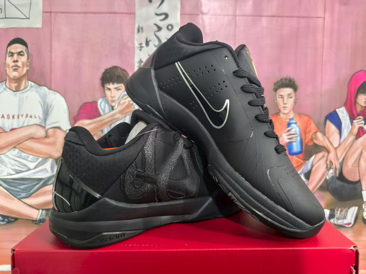 Pair of black Nike basketball sneakers displayed on a red shoebox, showing the side Swoosh and layered panels.