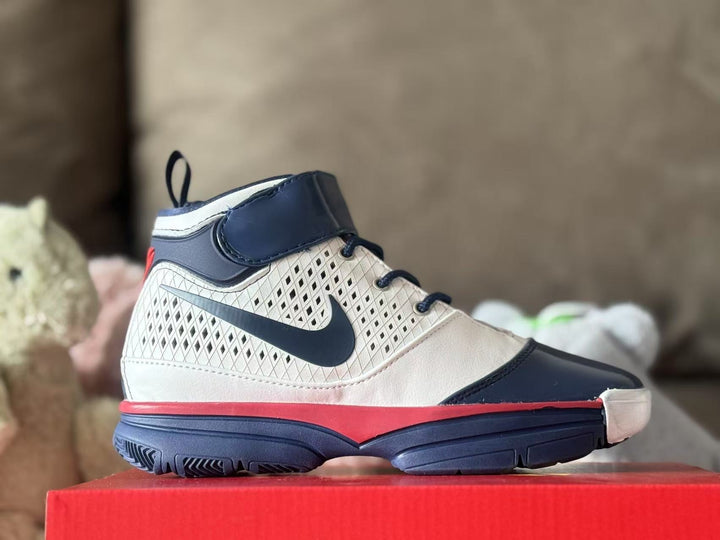 Side view of a white, navy, and red high-top kids' sneaker with a hook-and-loop ankle strap and patterned side panel.