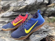 Angled front and side view of blue and red Kobe 11 sneakers, including the Kobe logo on the tongue