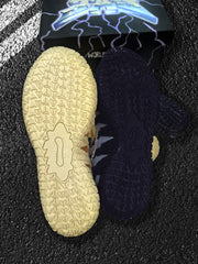 Bottom views of the pale yellow and dark blue outsoles with repeating traction patterns.