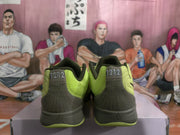 Rear view of the green Nike sneakers showing dark gray heel panels, stitched detailing, and 1212 heel markings.