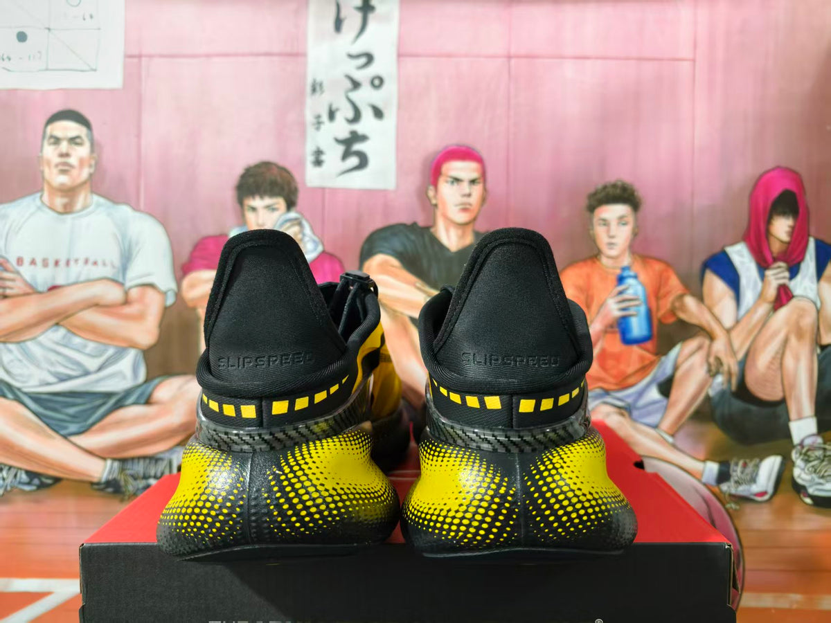 Rear view of black and yellow sneakers showing padded heels, yellow square accents, and dotted detailing.
