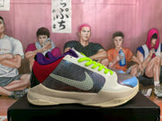 Side profile showing the dotted Swoosh, white and gray upper, blue and purple toe accents, green laces, and Nike Zoom midsole marking.