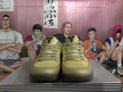 Front view of gold-toned Nike basketball shoes with matching laces, black tongue emblems and gray collars.