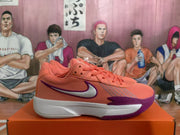 Side profile of a pink Nike basketball sneaker with a purple swoosh outline, white midsole, and purple outsole.