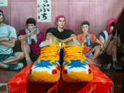 Front view of orange Nike sneakers with yellow laces and multicolor graphic uppers.