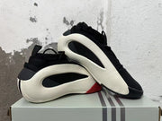Pair of black sneakers with white sculpted side frames and red accents