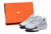 Pale grey Nike shoes with purple accents beside an orange Nike shoe box