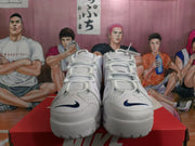 Front view of white Nike sneakers showing deep blue Swoosh accents, laces and perforated toe panels.