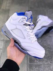 Front three-quarter view showing white laces, a grey tongue, blue branding, and blue outsole accents.