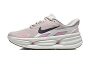 Side view of a pale pink and gray Nike sneaker with a black Swoosh and sculpted white sole