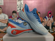 Angled view of the blue sneaker pair highlighting the red sidewall accents, gray outsole, and blue upper.