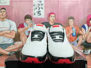 Front view of white Jordan shoes with patterned black laces and red-and-black toe accents.