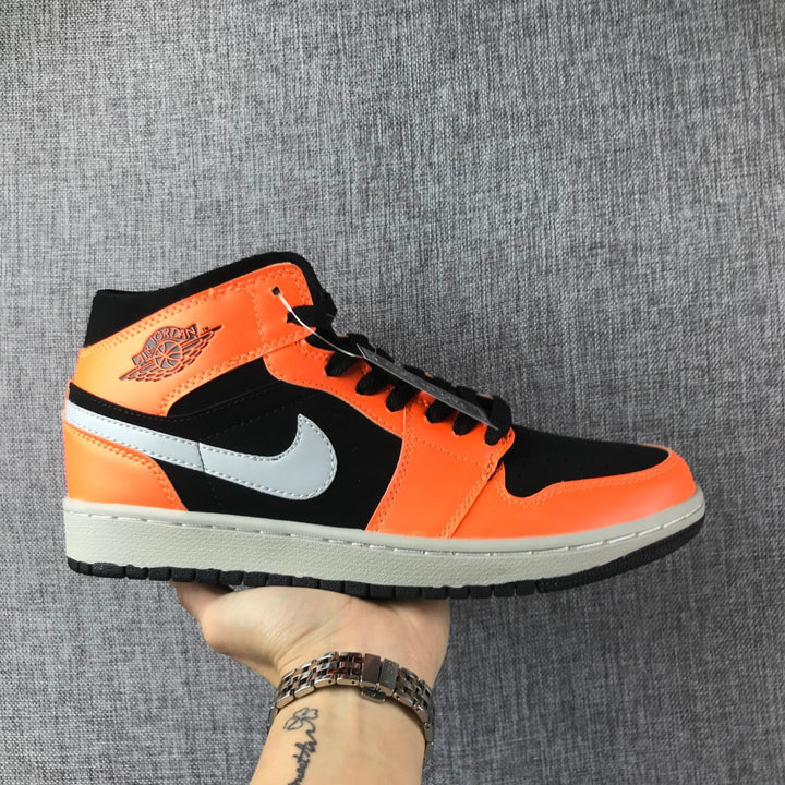 Side view of a black and orange Air Jordan 1 Mid sneaker with grey Swoosh and light grey midsole.