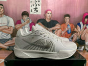 Side profile of a silver and white Nike basketball sneaker with a dark swoosh and textured midsole.