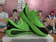 Angled view of the paired green sneakers showing the black toe and heel panels, textured uppers and sculpted soles.