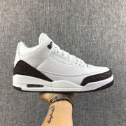 Side view of a white and brown Jordan Air Jordan 3 sneaker resting on a hand.