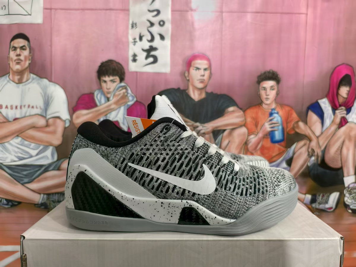Side view of white and gray Nike basketball sneakers with a black Swoosh, patterned upper, and speckled midsole.