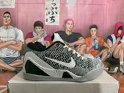 Side view of white and gray Nike basketball sneakers with a black Swoosh, patterned upper, and speckled midsole.