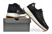 Side and heel views of black sneakers displayed beside a shoebox.